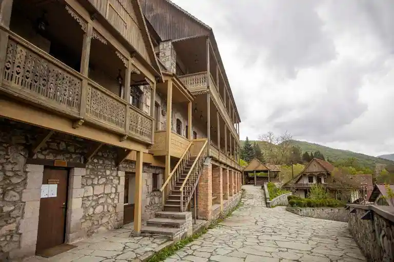 Muestra una calle de Dilijan con un edificio de piedra y madera de vacaciones en Armenia