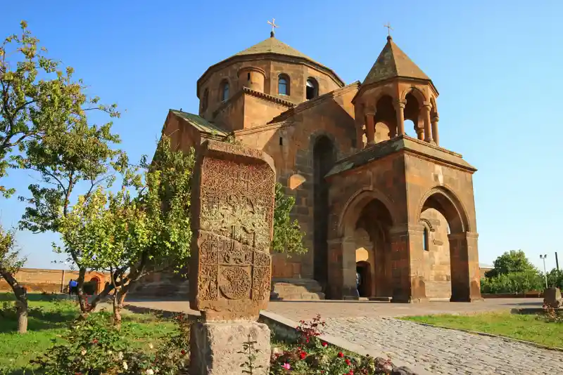 Show the Saint Hripsime Church in Armenia from the front with some small trees on the left side.