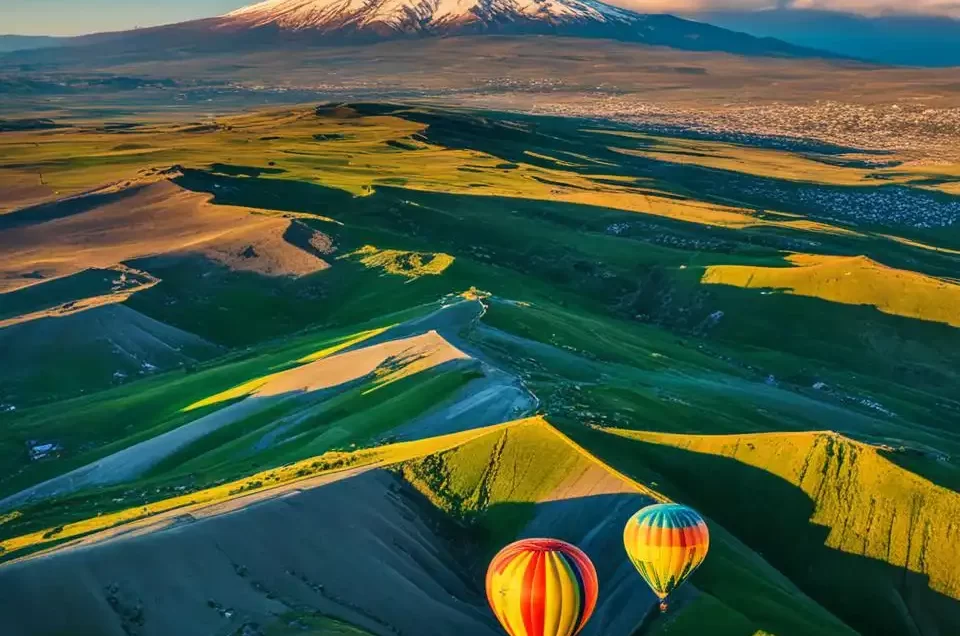 Aparece dos globos en un paisaje verde con una montaña nevada al fondo indicando lo que se puede hacer de Turismo en Armenia